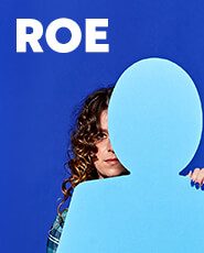 A woman stands behind a blue cut-out figure of a person. Text reads "Roe"
